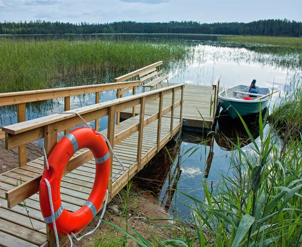 Βάρκα με μια ξύλινη προβλήτα με μια σανίδα σωτηρίας στη λίμνη — Φωτογραφία Αρχείου