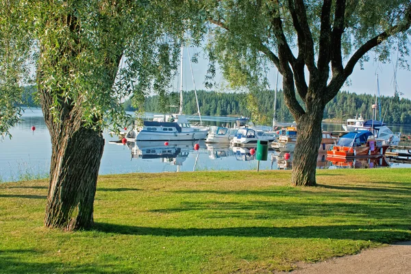 Jachten aangemeerd op het meer met de bomen op de bank in finland — Stockfoto