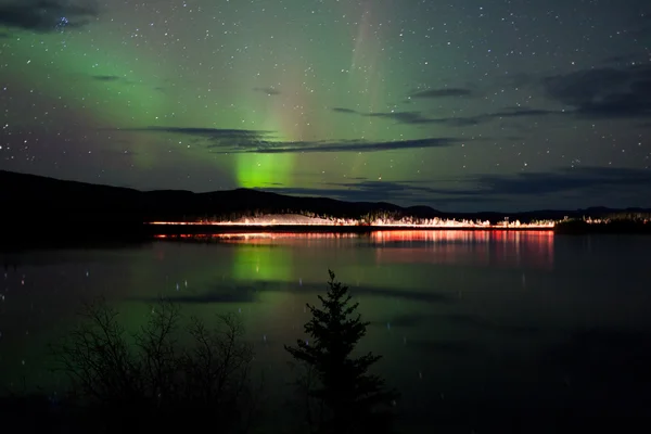 Estrelas e luzes do norte sobre estrada escura no lago — Fotografia de Stock