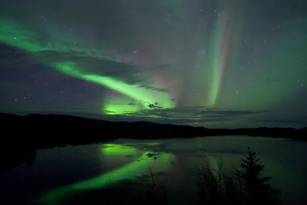 Sterne und Nordlichter über dunkler Straße am See — Stockfoto