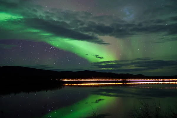 Stelle e aurore boreali sulla strada buia al lago — Foto Stock