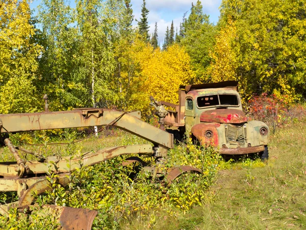 Rostig lastbil och väghyvel glömt i höst skog — Stockfoto