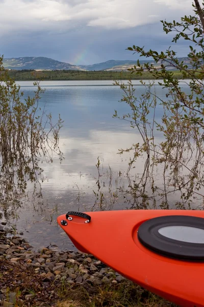 Kayak on shore in the willows alongside a lake — Stock Photo, Image