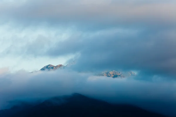 Nubes oscuras al atardecer sobre altos picos de montañas escarpadas — Foto de Stock