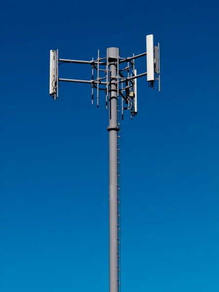 Mobile phone antennas on metal tower on blue sky — Stock Photo, Image