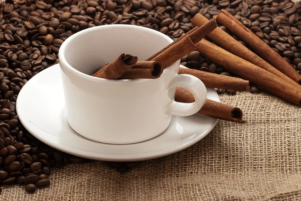 Biała kawa kubek, fasoli i cynamon laski na zwolnieniu — Zdjęcie stockowe