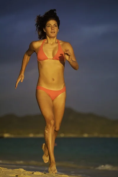 Young woman running on the beach at sunrise — 图库照片
