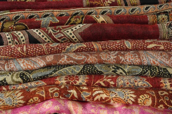 Pilha de tecidos coloridos dobrados e xales — Fotografia de Stock