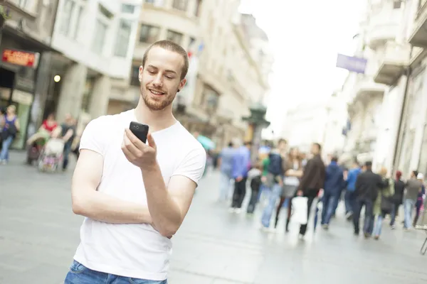 Giovane con cellulare a piedi in città — Foto Stock
