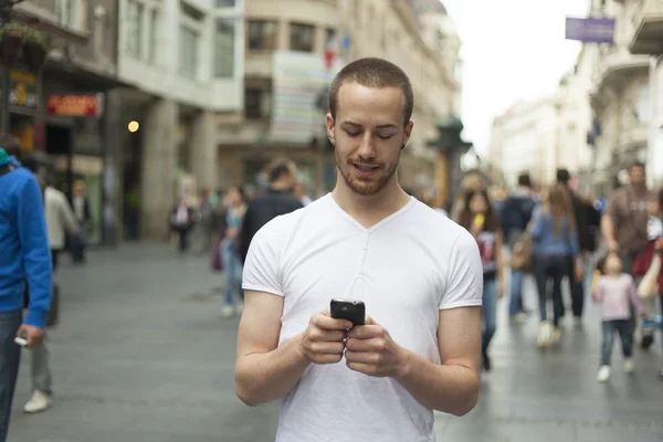 Людина з мобільним телефоном, що йде по вулиці — стокове фото