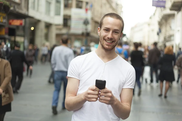 携帯電話の歩行を持つ男の笑みを浮かべてください。 — ストック写真