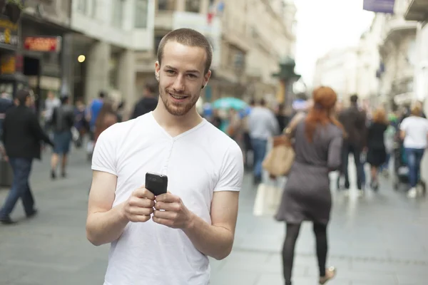 Homme souriant avec téléphone portable marche — Photo