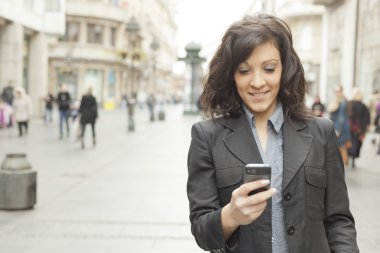 Girl with smartphone walking on city clipart