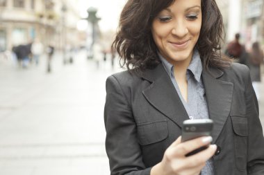 Businesswoman with smartphone walking on street clipart