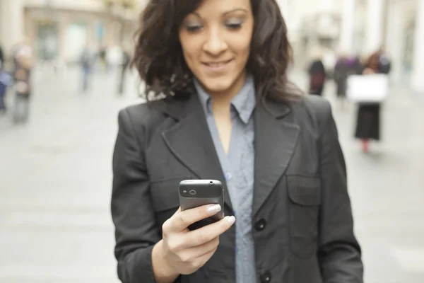 Businesswoman with smartphone walking on street. phone in focus — Stock Photo, Image