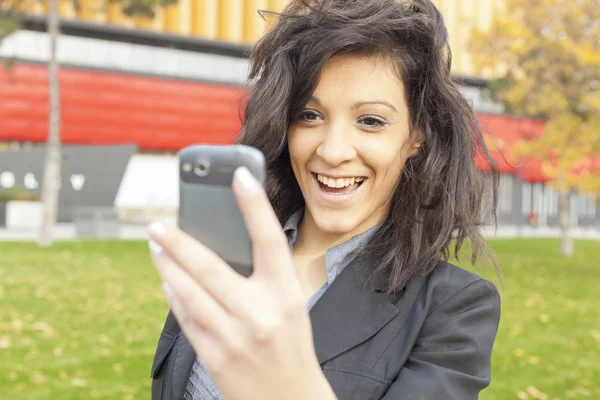 Νεαρή γυναίκα με χαμόγελο αστείο μαλλιά χρησιμοποιώντας κινητό περπάτημα — Φωτογραφία Αρχείου