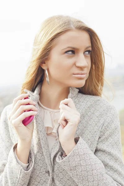ピンクの携帯電話を歩くと美しい若い女性 — ストック写真