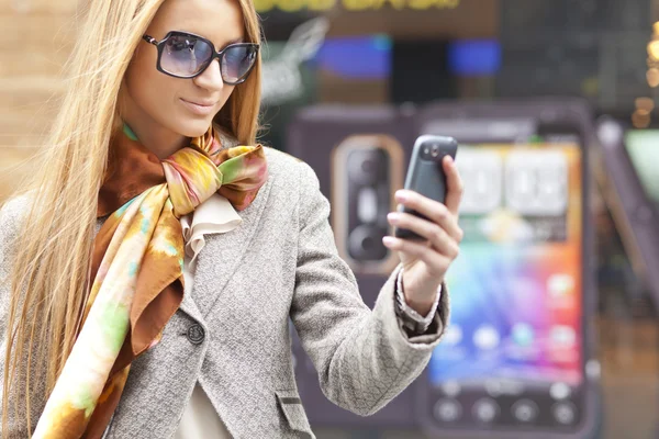 Kvinna med solglasögon och mobiltelefon promenader — Stockfoto