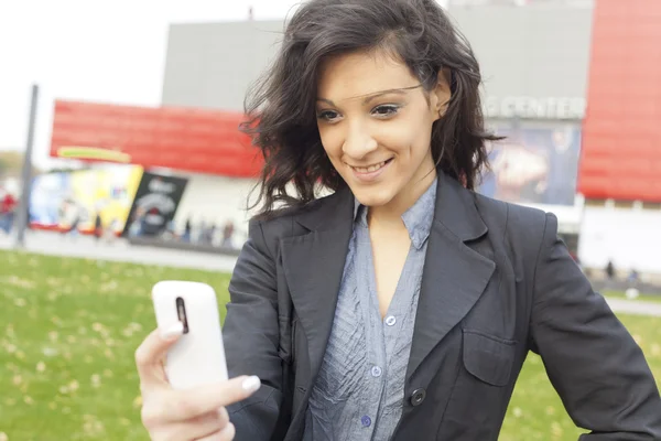 Jonge vrouw met mobiele telefoon wandelen — Stockfoto