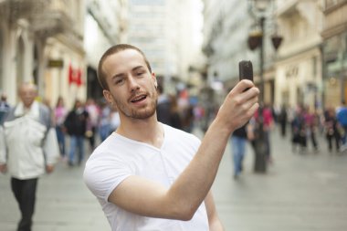 Akıllı telefonu olan genç bir adam.