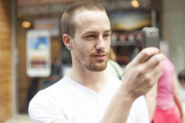 Sokaktaki adamlar cep telefonlarıyla fotoğraf çekiyorlar.