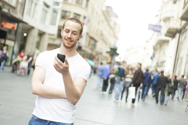 Молодий чоловік з мобільним телефоном, що йде містом — стокове фото