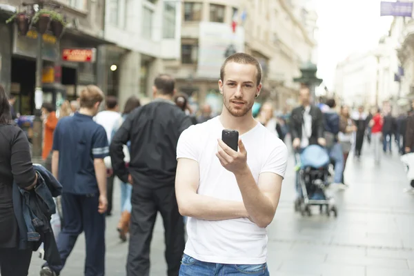 Νεαρός άνδρας στην πόλη με το κινητό τηλέφωνο — Φωτογραφία Αρχείου