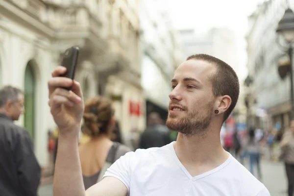 Fotógrafo urbano con teléfono mobila caminando calle cruzada y ph — Foto de Stock