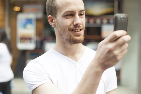 笑顔の男性が通りに携帯電話で撮影 — ストック写真