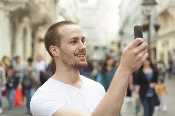 stock image Smiling man photographing with smartphone