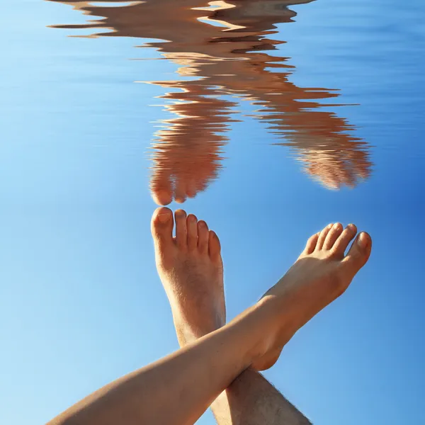 Human legs on the blue water in summer — Stock Photo, Image