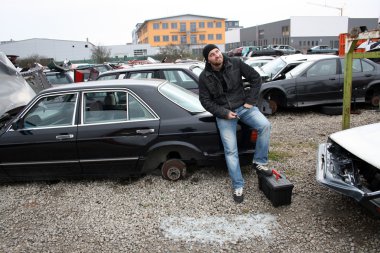 Man looking at the scrap yard car parts clipart