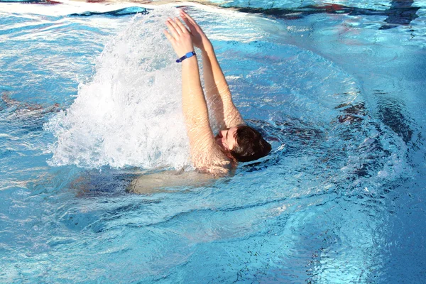 Młody mężczyzna nauka pływania stylem grzbietowym w basenie — Zdjęcie stockowe