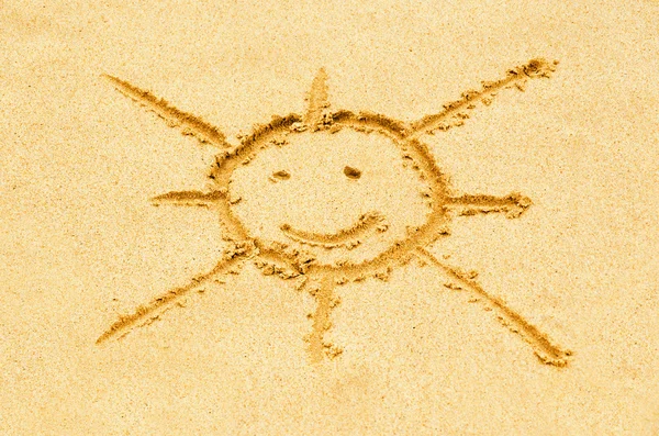 stock image Smiling sun drawn on a sandy beach