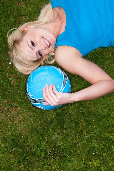 Mladá blonďatá žena ležící na trávě — Stock fotografie