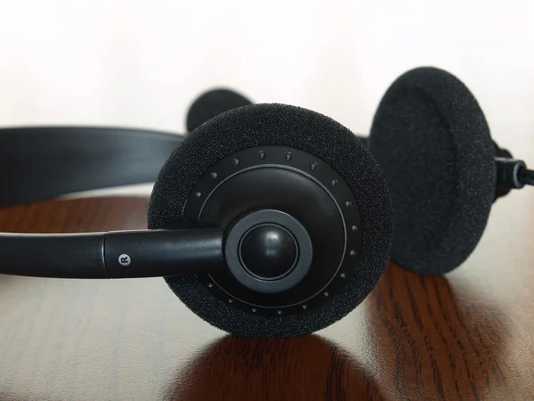 Czarny słuchawki na drewnianym stołem. — Zdjęcie stockowe