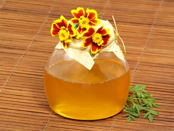 Honing kruik en gele bloemen. — Stockfoto