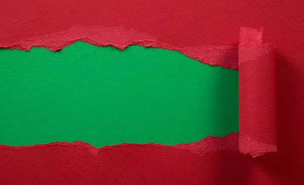 Разорванная красная бумага на зеленом фоне — стоковое фото