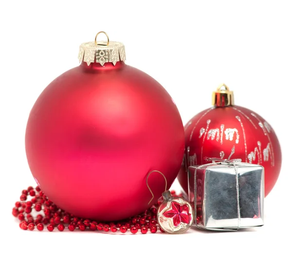 Три рождественских шарика с красными бусами и маленьким подарком — стоковое фото