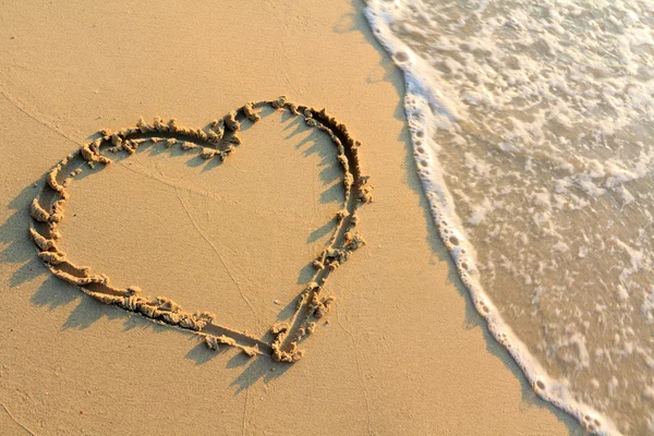 Воды брызги на форме сердца рисовать на пляже — стоковое фото