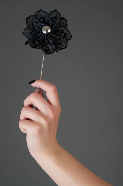 Černá umělá květina v ženské ruce — Stock fotografie