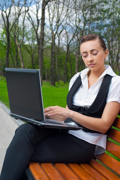 Молодая женщина скамейка с ноутбуком — стоковое фото