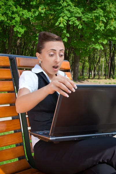 Amazed oung woman with laptop sitting on bench — Stock Photo, Image