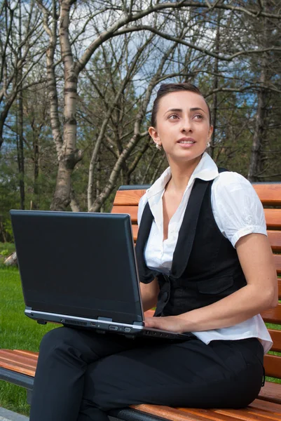 Mujer joven sentada en el césped con portátil —  Fotos de Stock