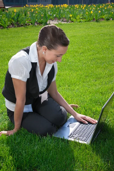 Mladá žena seděla na trávníku s notebookem — Stock fotografie