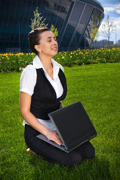 Jovem mulher sentada no gramado com laptop — Fotografia de Stock
