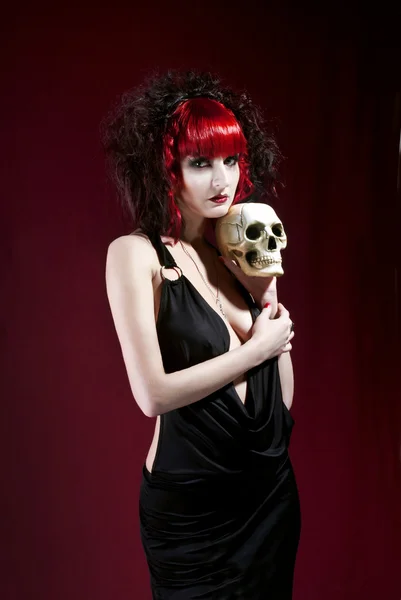 Studio portrait of young pale woman in black dress holding skull — Stock Photo, Image