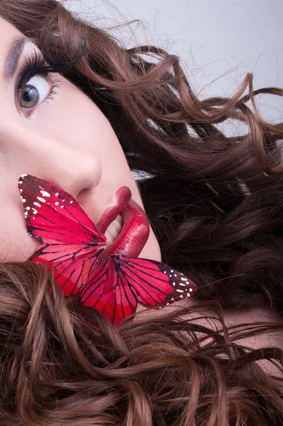 Руда кучерява жінка з червоною метеликом на губах — стокове фото