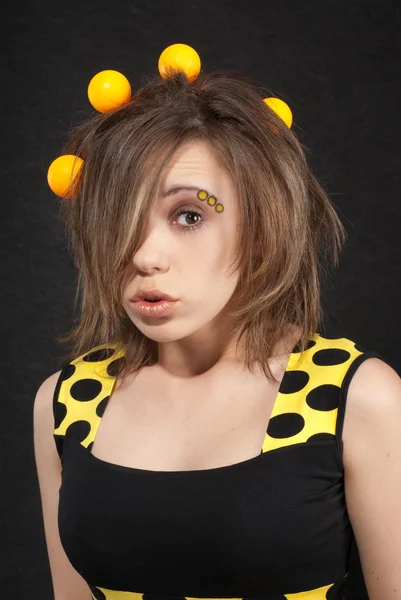 Retrato de estudio de mujeres jóvenes divertidas con bolas amarillas en el pelo sobre fondo negro —  Fotos de Stock