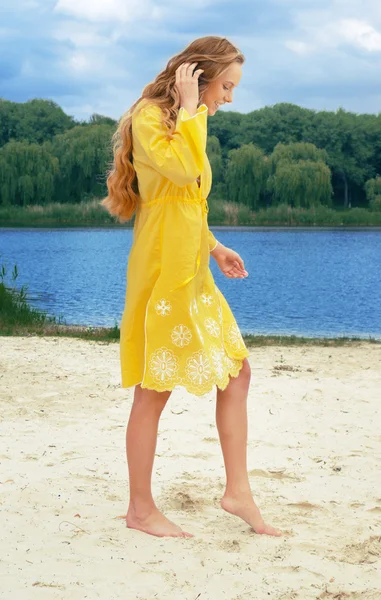 リバー ビーチに黄色の衣装に若い長髪の魅力的な女性 — ストック写真